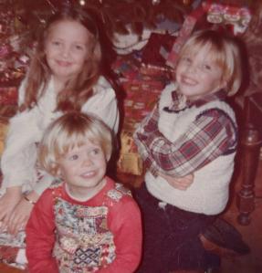 Two smug older children pose with a sweet little brother.